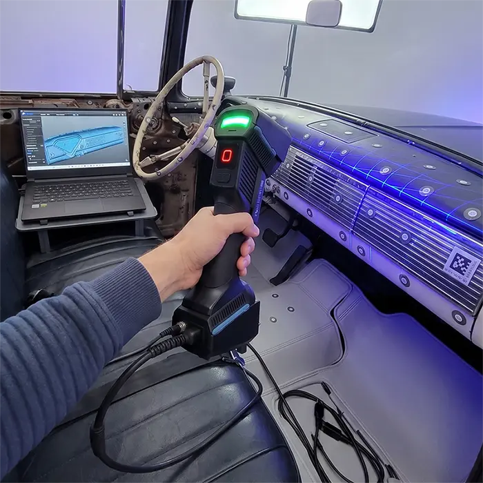A Prozix technician using the Einscan FreeScan UE Pro laser scanner to capture high-detail 3D geometry of a vehicle's dashboard and upholstery.