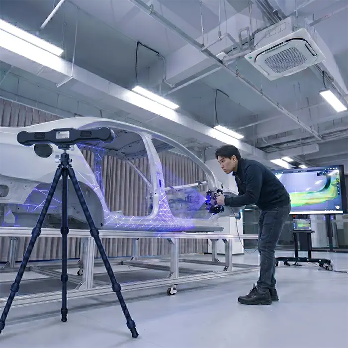 A technician using the Prozix Einscan Trak Nova metrology 3D scanner to capture high-precision data from a vehicle chassis.